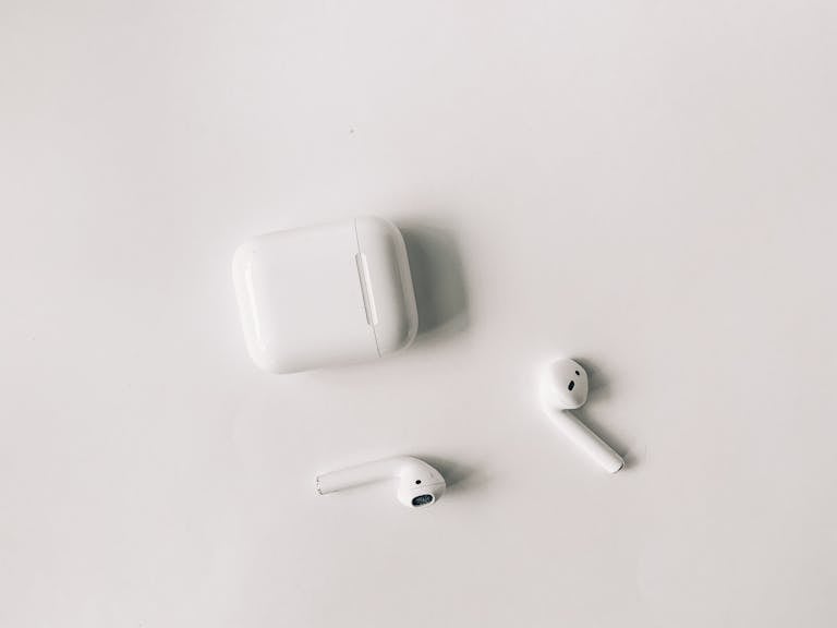 Clean minimalist flat lay featuring wireless earbuds and case on a white background.