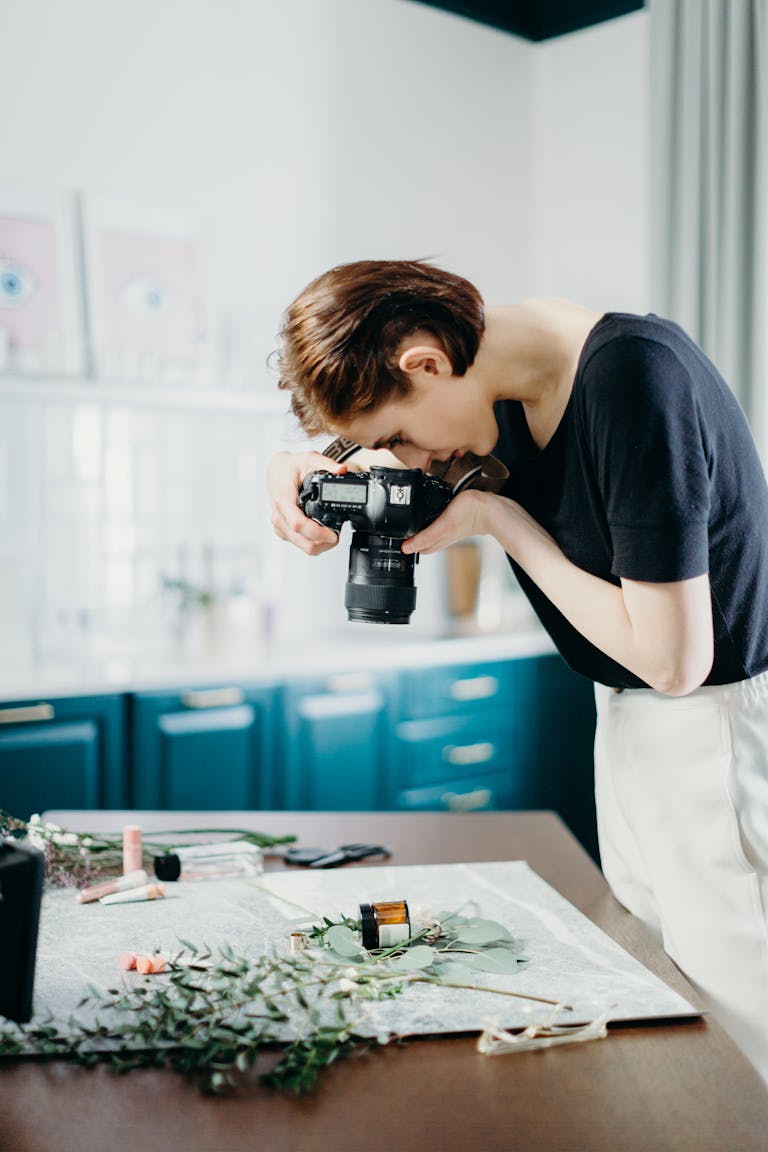 Woman taking photos of a still life setup with camera in a modern indoor setting.