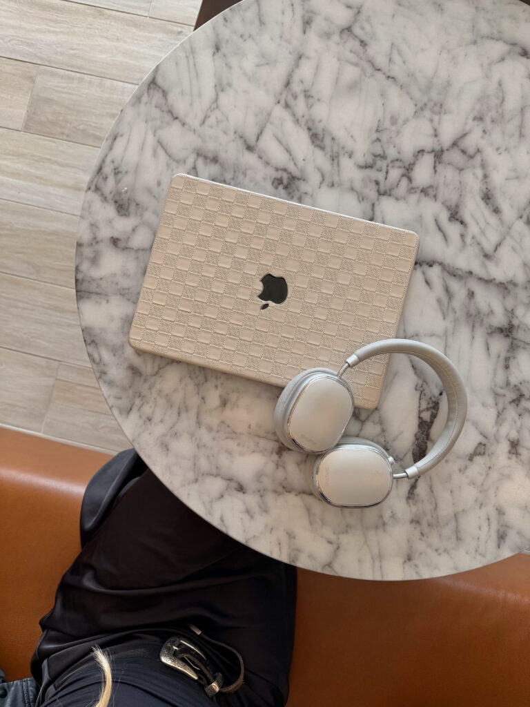 Marble table with a closed laptop and white headphones, calm minimalist work setting.